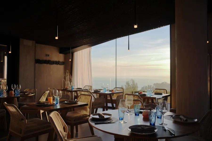 Restaurantens spisesal i solnedgangen, med bordene langs det gennemgående vinduesparti