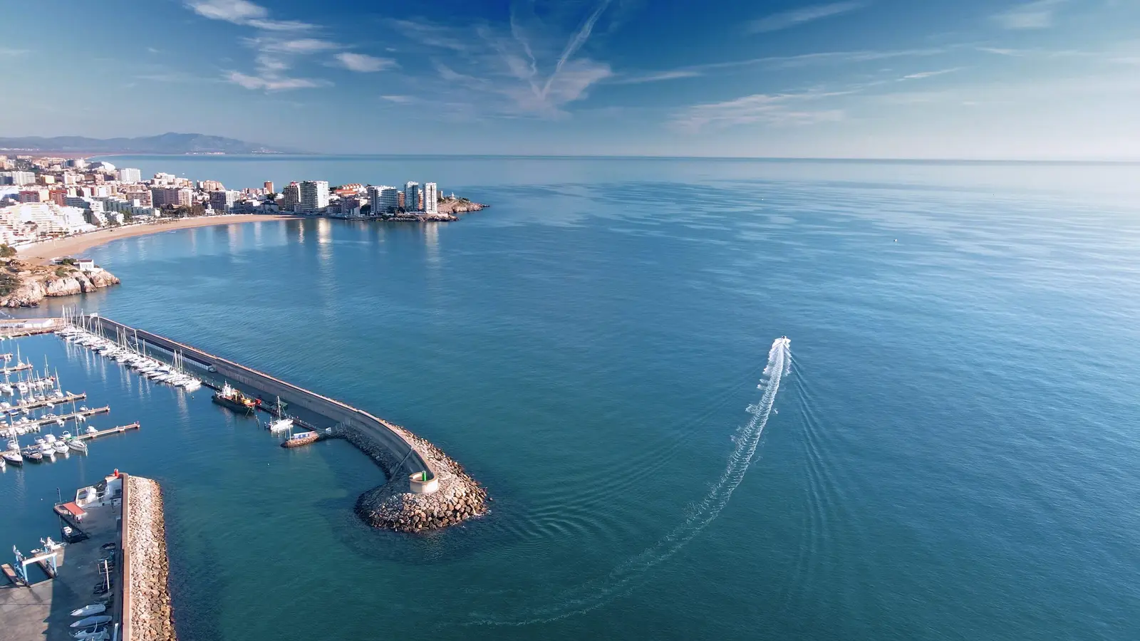 El puerto de Oropesa del Mar con las embarcaciones amarradas y una lancha saliendo a mar abierto