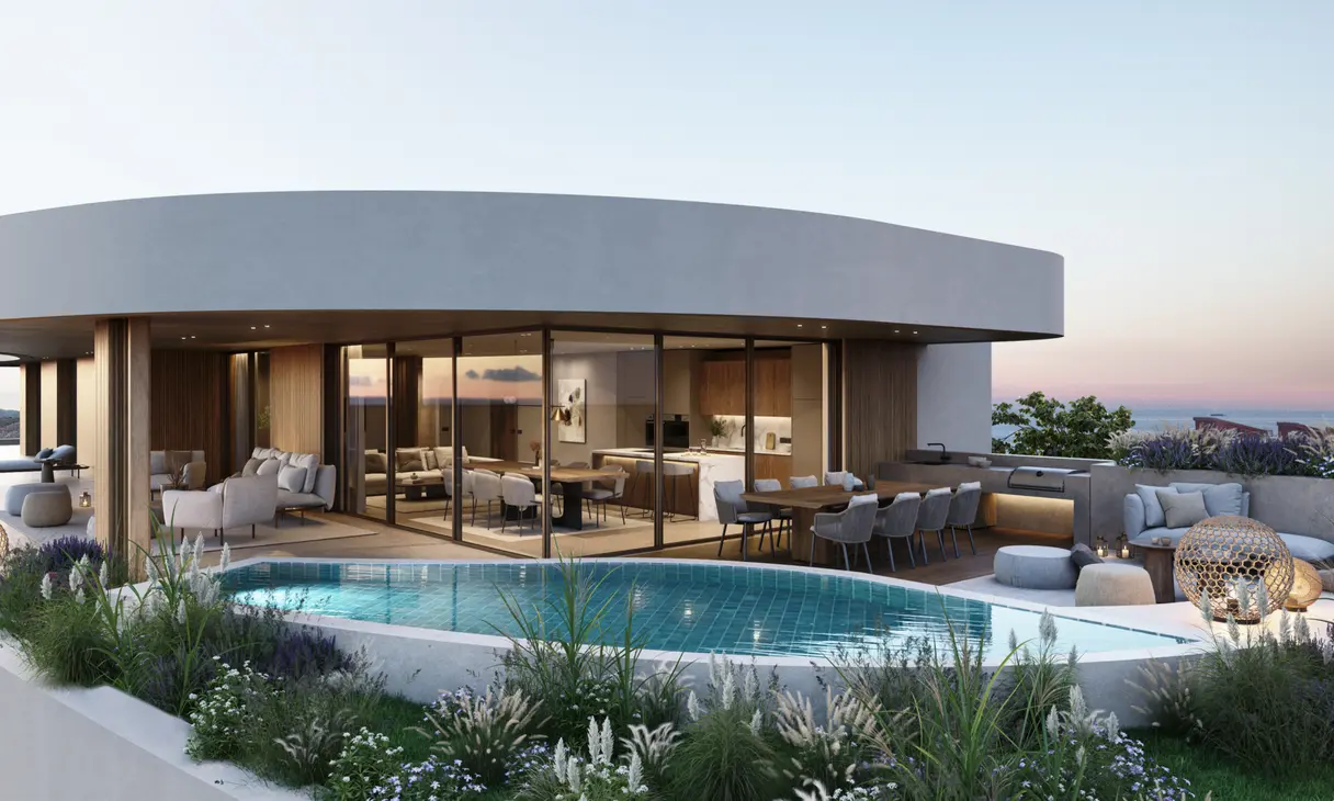 Terraza de un ático al atardecer: piscina privada, cocina exterior y el salón acristalado detrás