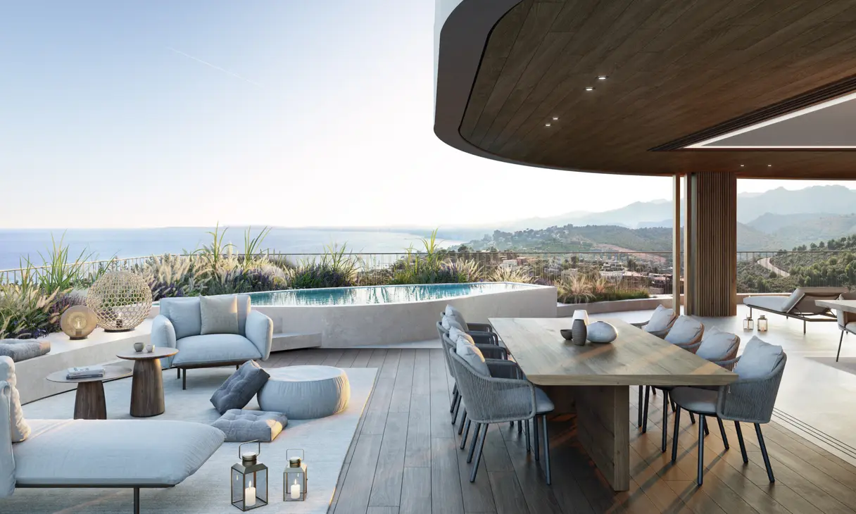 Comedor exterior de un ático bajo el porche, con la piscina desbordando sobre la costa