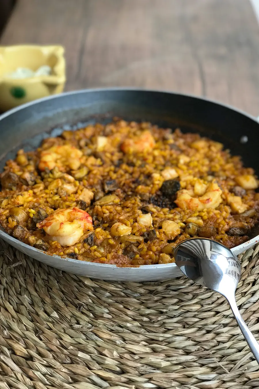 Paellera de arroz con gambas y marisco recién hecho, con la cuchara apoyada en el borde