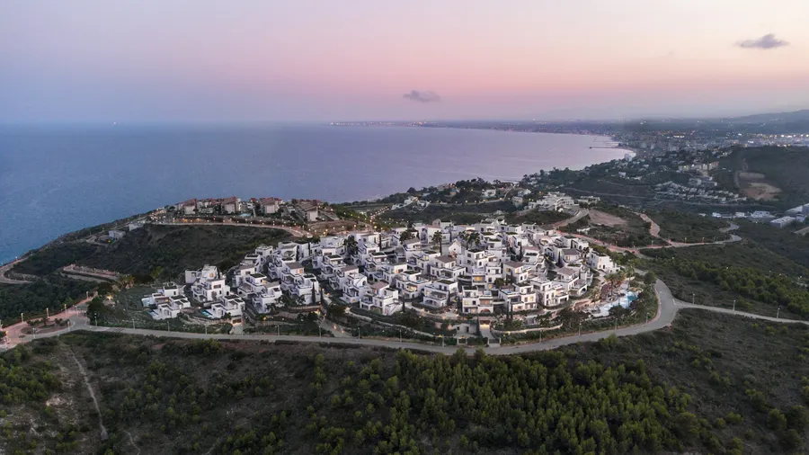 Rendering af landsbyen Azure set fra luften, med de hvide huse på skråningen og havet i baggrunden